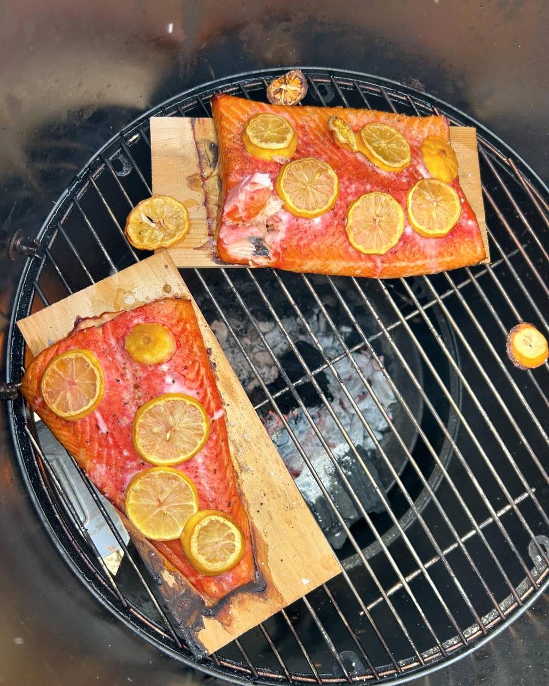 Twee zalmfilets met citroen op plankjes op de barbecue