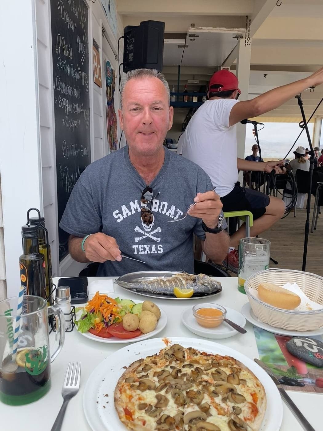 Gert aan tafel op een zonnig terras met pizza en salade