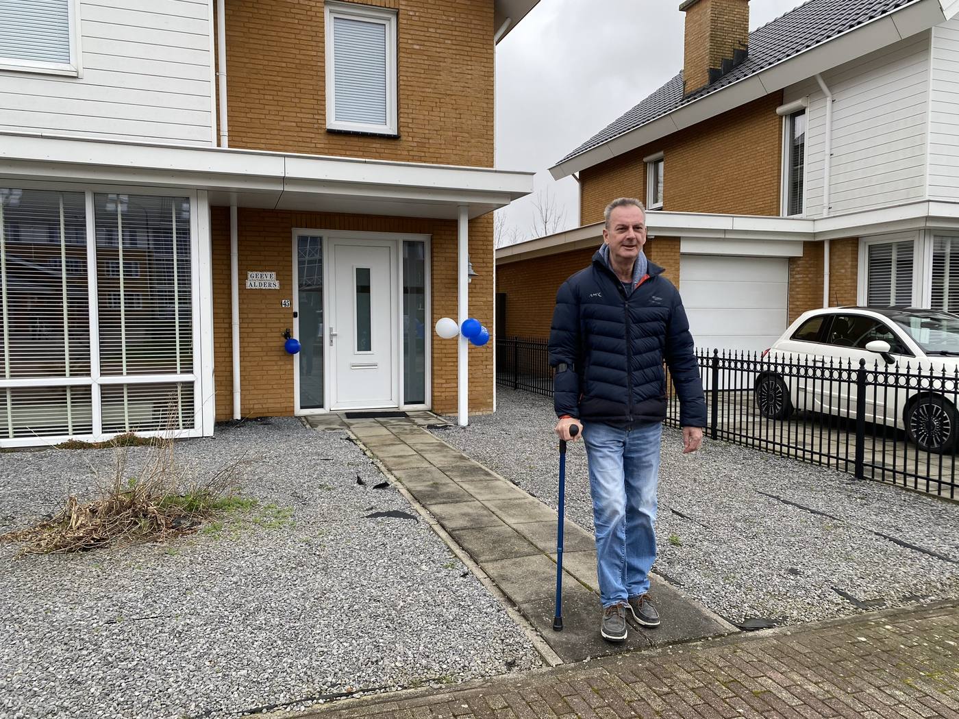 Gert loopt met een wandelstok over het pad naar zijn voordeur