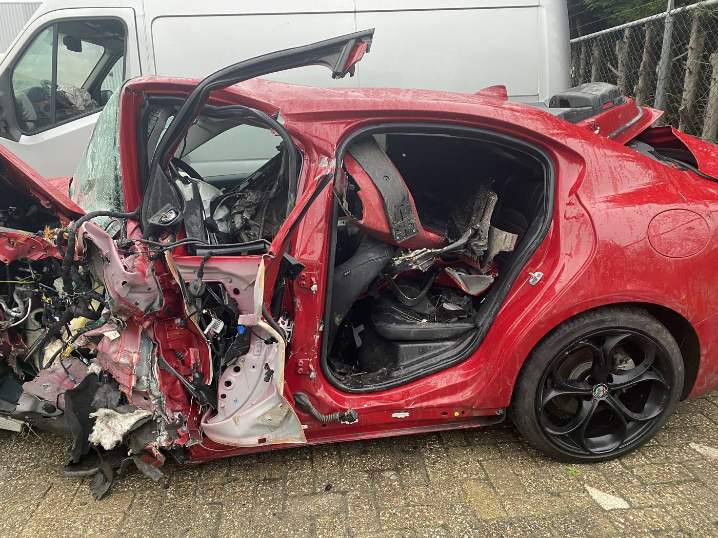 De rode auto na het ongeluk, met de linkerkant volledig ingedeukt